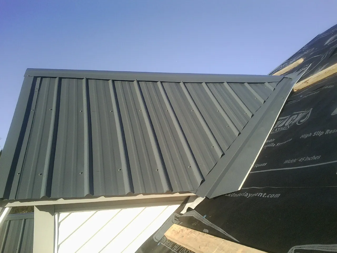 Gray metal roof panels going on over a garage gable in Springville